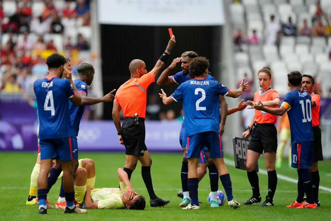 El &aacute;rbitro Adel Al Naqbi (c) le saca la tarjeta roja al dominicano Edison Azcona (d) tras una acci&oacute;n contra Pau Cubars&iacute; (en el suelo) durante el partido del Grupo C de f&uacute;tbol masculino de los Juegos Ol&iacute;mpicos de Par&iacute;s 2024 disputado en el Estadio de Burdeos. EFE/ M. Reino