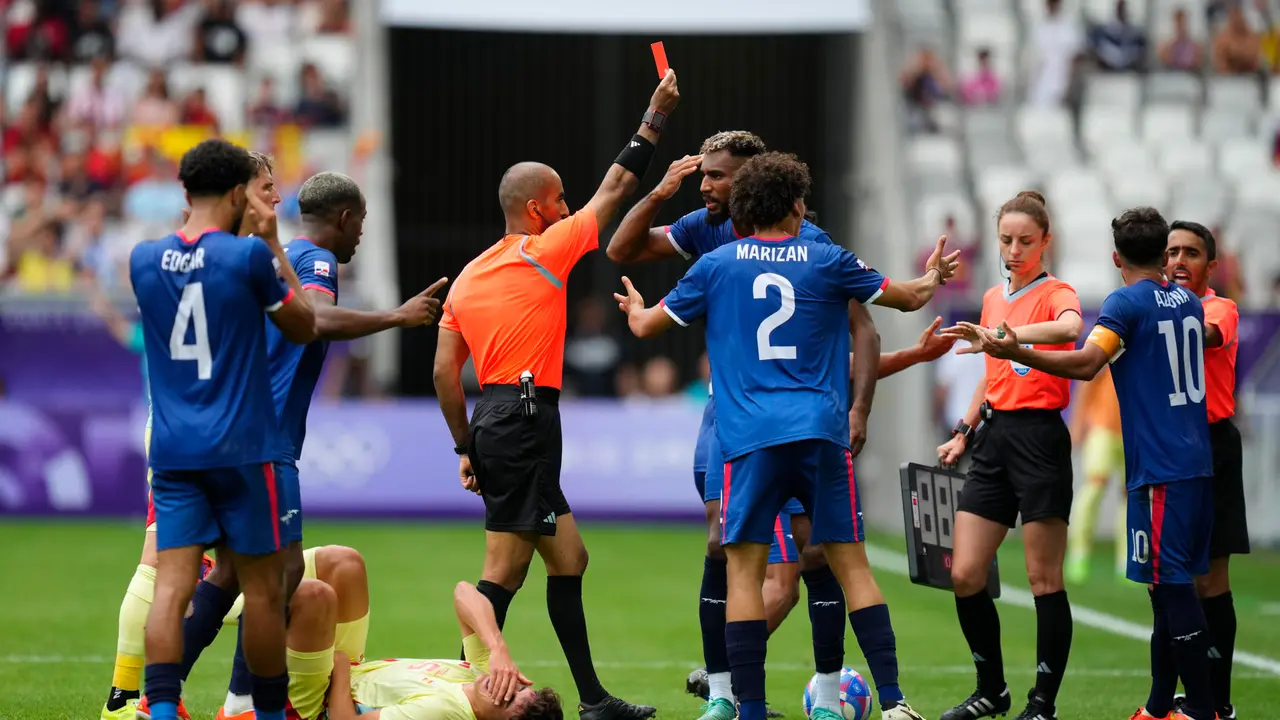 El &aacute;rbitro Adel Al Naqbi (c) le saca la tarjeta roja al dominicano Edison Azcona (d) tras una acci&oacute;n contra Pau Cubars&iacute; (en el suelo) durante el partido del Grupo C de f&uacute;tbol masculino de los Juegos Ol&iacute;mpicos de Par&iacute;s 2024 disputado en el Estadio de Burdeos. EFE/ M. Reino